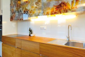 Kuchyň kombinující dřevěnou dýhu, bílé lamino a originální prosklené skříňky s květinovým dekorem je specialitou paní architektky. FOTO: Dano Veselský