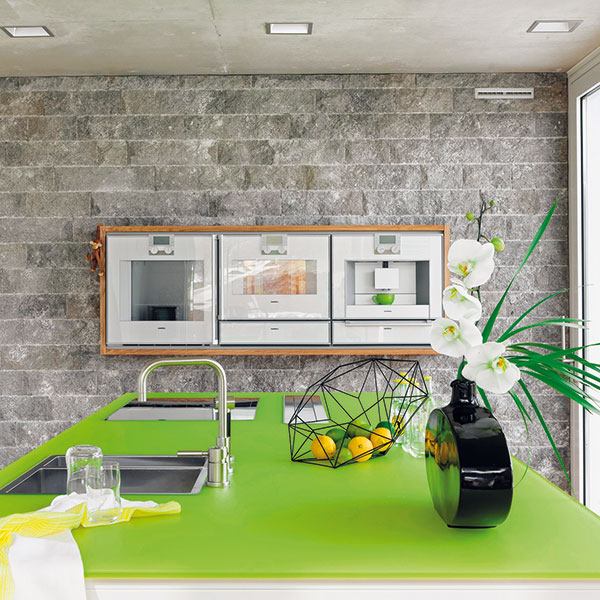 Dekorativní stěna, obložená jurským vápencem, dominuje kuchyni při pohledu z jídelny. V ergonomické výšce je v ní zabudované trio spotřebičů skryté za sklem osazeným v dubovém rámu. FOTO PROFIMEDIA
