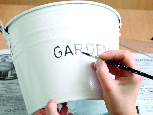 Nápis vymalujte černou barvou na kov nebo jinou univerzální vrchní barvou. Do kbelíku vložte květiny s vodou.