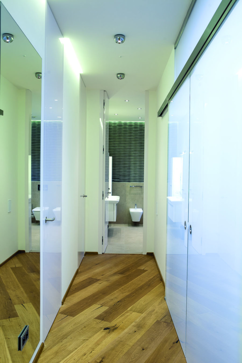 Chodbě do křídla majitelů a dcerky dominují průsvitné skleněné dveře. Dvoje pokojové vlevo, šatní posuvné vpravo. Rovně je společná toaleta s koupelnou.