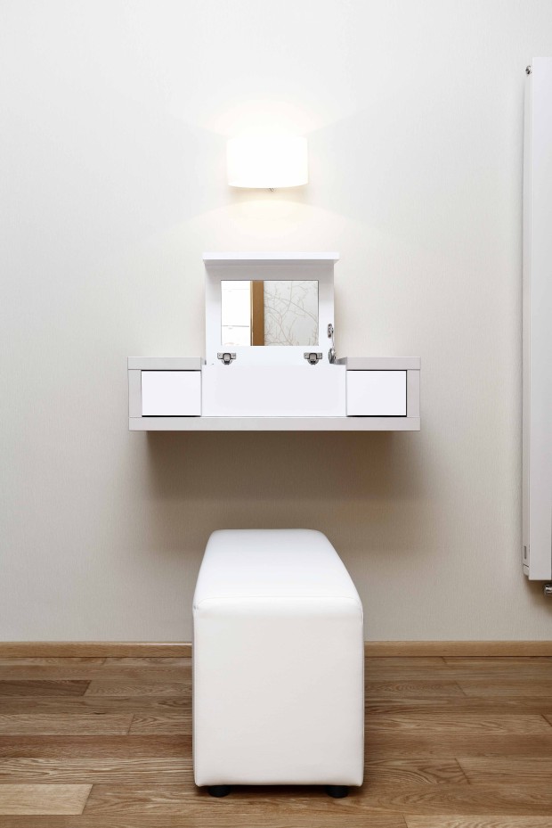Otevírací toaletní stolek je vyroben na míru. I v ložnici je, podobně jako v obýváku a kuchyni, použita decentní kombinace několika odstínů bílé a zemitých tónů, zde je však, na rozdíl od kuchyně, povrch nábytku matný.