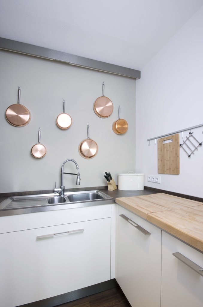 Stříbrné akcenty se vyskytují v celém bytě, například v podobě kulatých svítidel. Jen kuchyni dominuje měděná v podobě kvalitního měděného nádobí, které je jako chlouba vystaveno zavěšené na stěně nad kuchyňskou linkou.