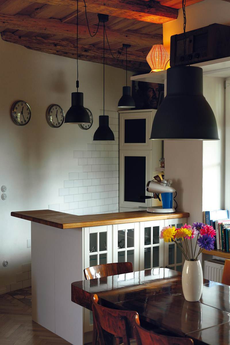 Motiv obnažené cihlové zdi z obývací části se opakuje i v kuchyni, v kombinaci s bílou linkou a doplňky působí romanticky.