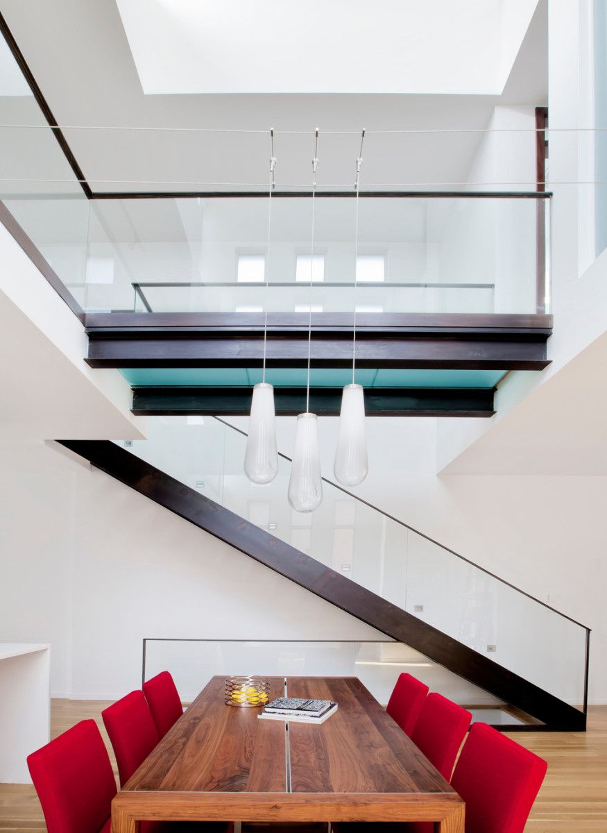 Lávka ve druhém nadzemním podlaží překlenuje otevřený prostor obývací části a spojuje dvě galerie s ložnicemi. Lustr nad jídelním stolem je z důvodu absence stropu zavěšený na ocelových lankách.
