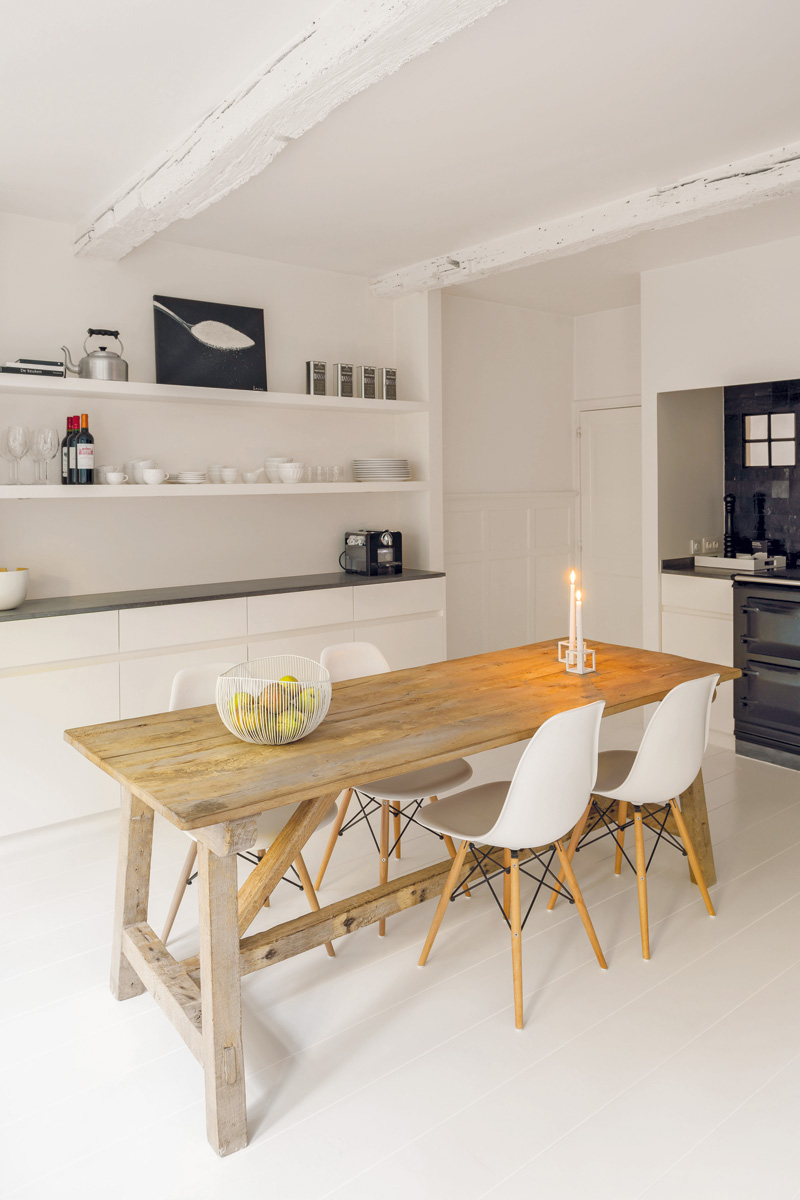 V kuchyni vytvářejí elegantní kontrast s bílými stěnami a jednoduchou bílou linkou lesklé černé plochy obkladaček, pracovních desek a spotřebičů s retro designem.