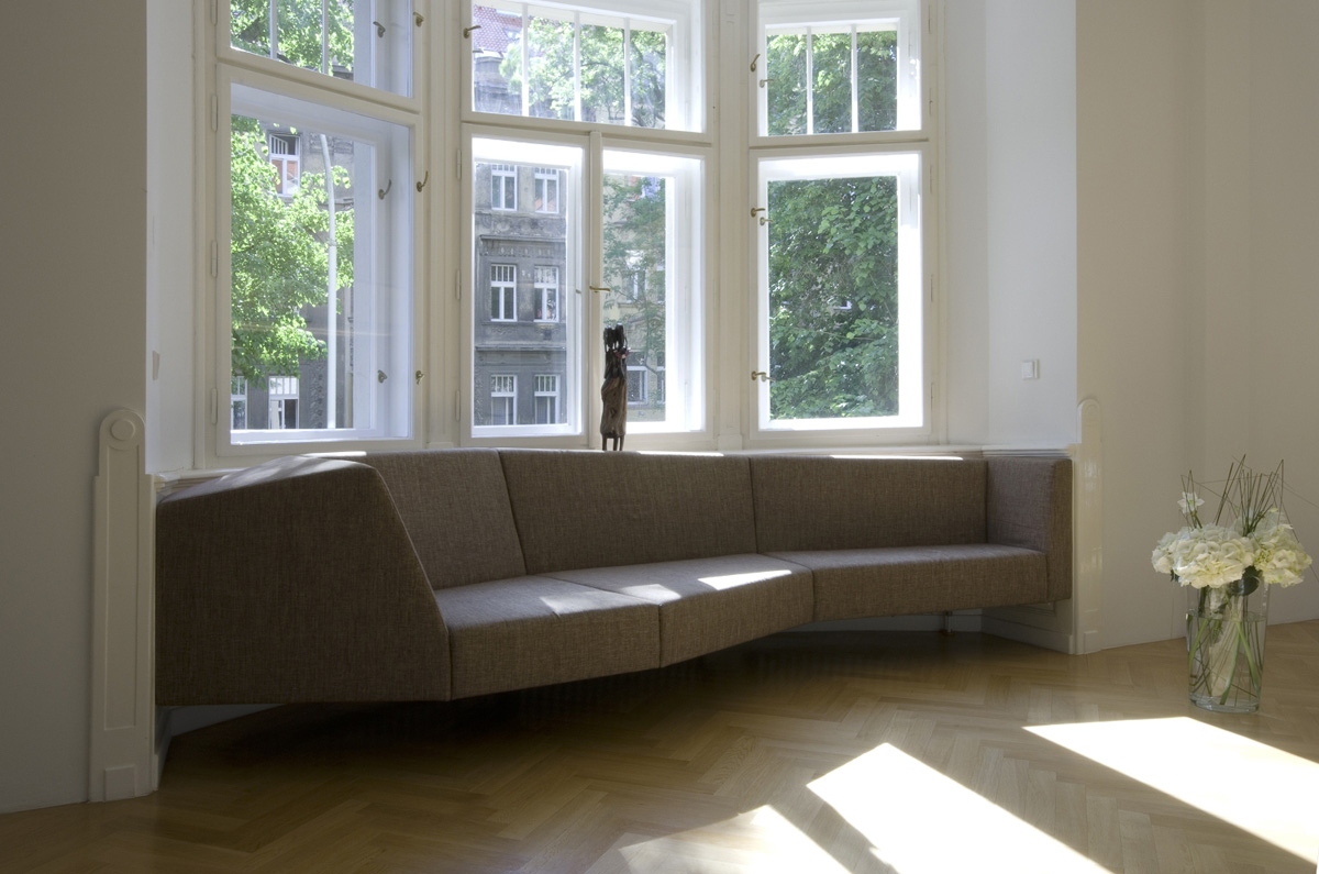 Originální sedačka pod oknem jako šedá skulptura doplňuje dřevem obložený výklenek. (foto: Jiří Ernest)
