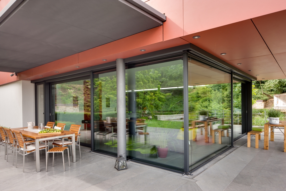 Transparentní prostor kuchyně a kryté terasy v přízemí. Konstrukčně jde o kombinaci posuvného systému Schüco ASS 70.HI s pevnými částmi z fasádního systému Schüco FW 50+.SI.