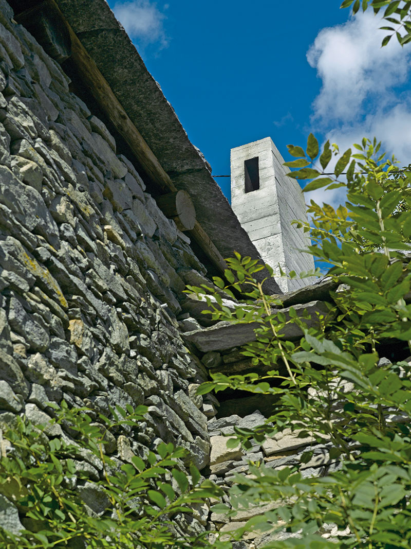 Betonový komín a skleněné dveře do zahrady jsou jedinými zvenčí viditelnými důkazy nového života v dvousetleté budově.
