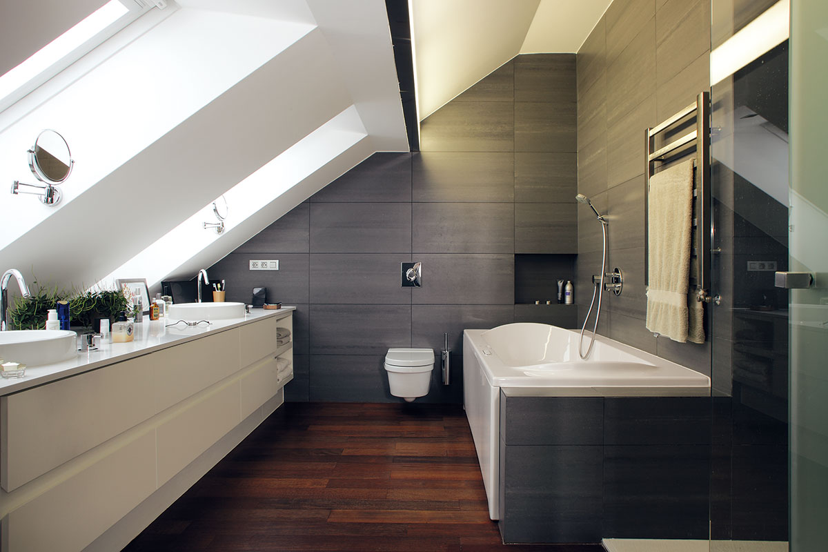Šedo-bílou kombinaci na dřevěném „základu“ najdeme i v rodičovské koupelně. Poskytuje skutečně královské pohodlí: velkou vanu, sprchový kout i dvě umyvadla. Foto Robert Žákovič