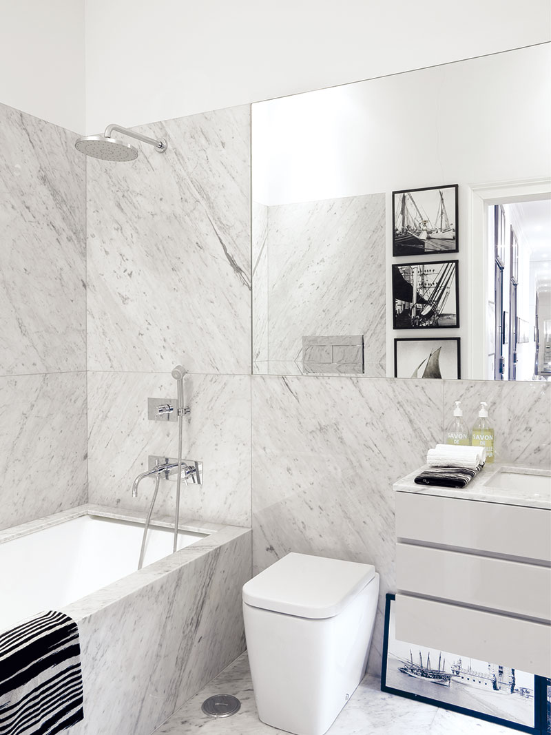 Decentní černo-bílou barevnou kombinaci, která je základem interiérů v celém bytě, najdeme i v koupelně s mramorovým obkladem u hlavní ložnice. Foto photopress.com