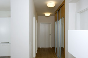 Pohled do chodby odhaluje praktické řešení úložných prostor s vestavěnými skříněmi.