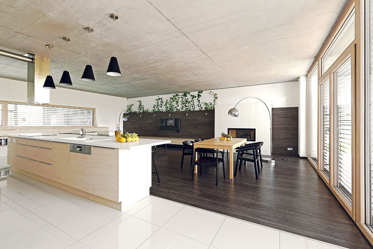 Funkční rozdělení hlavního obytného prostoru zvýrazňuje bílá kuchyňská dlažba kontrastující s tmavou laminátovou podlahou v obývacím pokoji.
