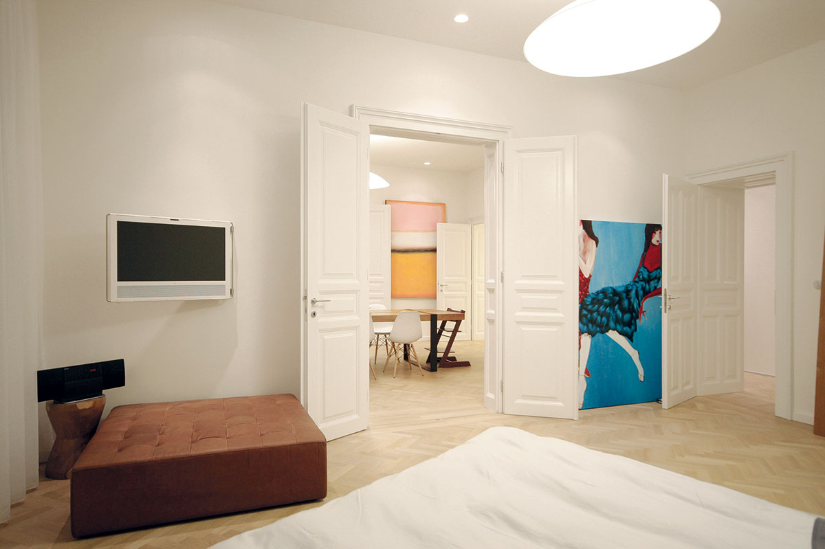 Pohled z ložnice přes všechny místnosti bytu. Rodina žije otevřeným způsobem, takže jim otevřené řešení dispozice vyhovuje a naplno využívají spojovací možnosti dvoukřídlých dveří.