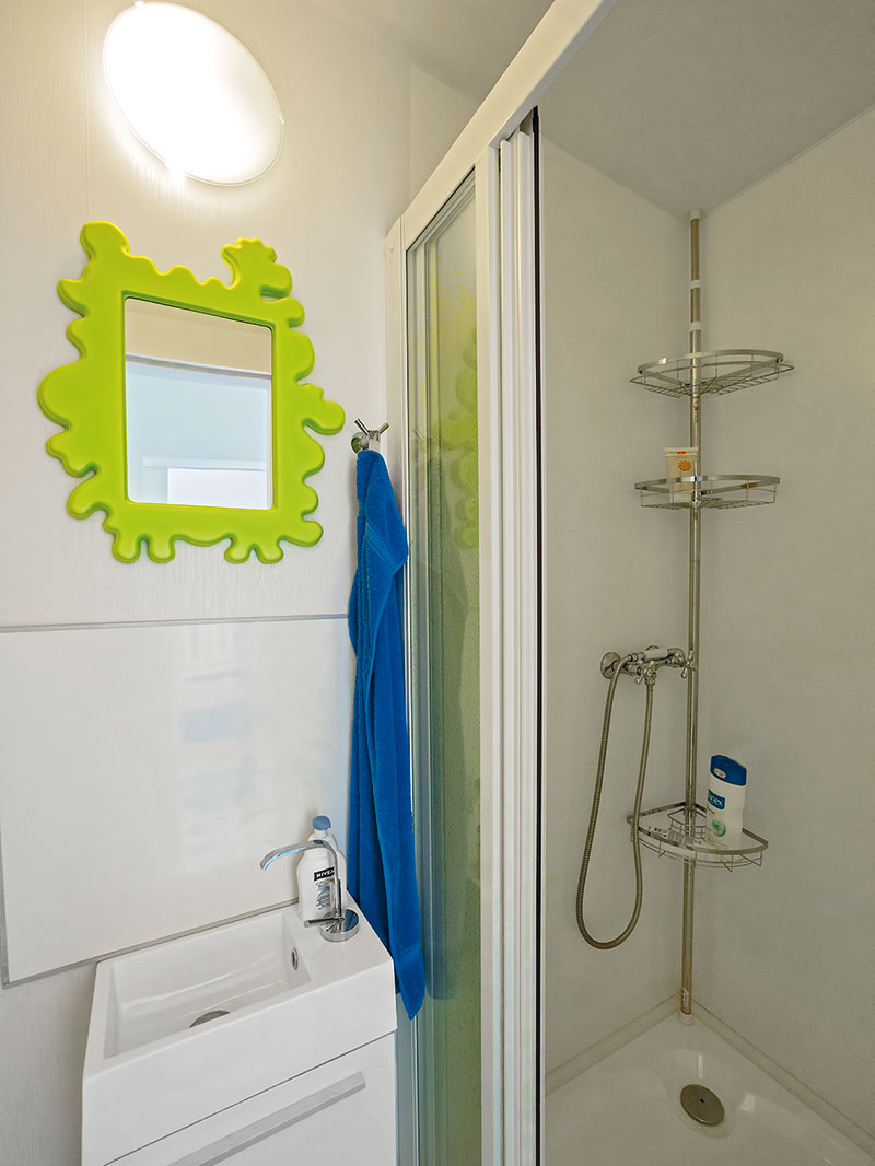 Koupelna s toaletou je malá, ale funkční. Vanu ve stísněnějších podmínkách nahradil sprchový kout. Bílá barva prostor opticky zvětšuje, svěžím akcentem je zrcadlo se zeleným rámem. FOTO KATARÍNA BAKO