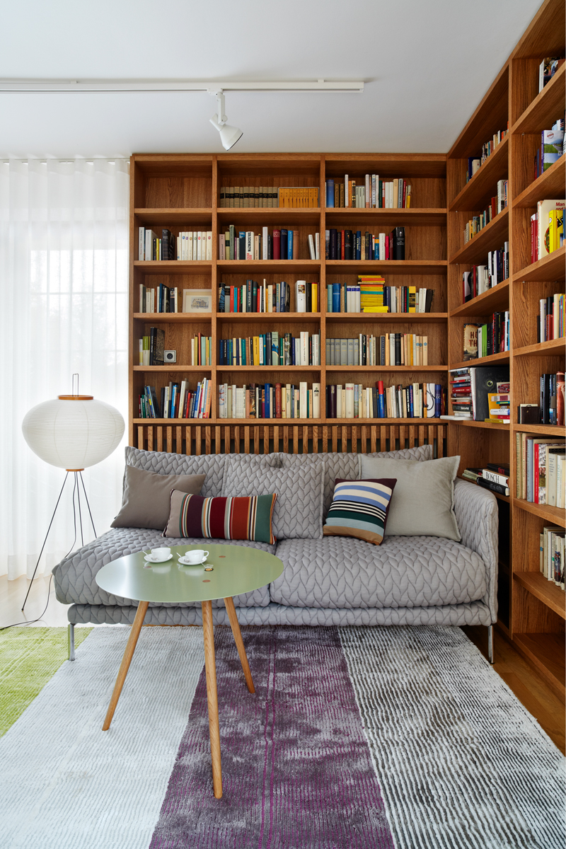 Dubová knihovna s rohovou sedačkou Moroso − celek doplňuje servírovací stolek, podle návrhu architekta (v bruselském stylu) a stojací svítidlo od Vitry.