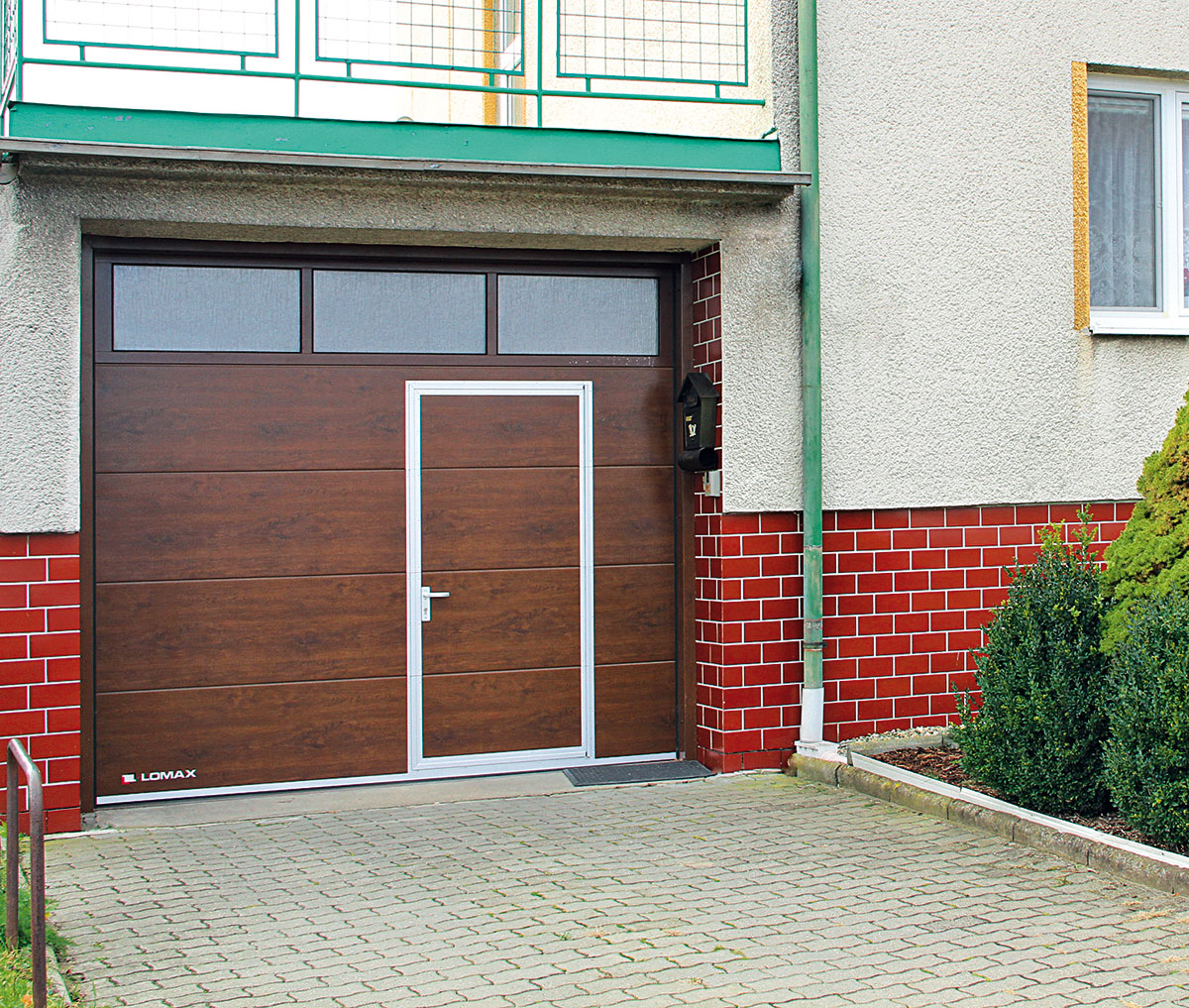 Do sekčních vrat lze vsadit zasklení nebo malé vstupní dveře, případně mohou mít vstupní dveře do domu tentýž design jako garážová vrata. FOTO LOMAX
