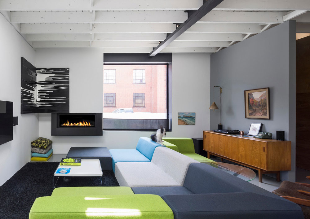 Obývák na rozdíl od zbytku interiéru hraje barvami díky velkorysé pohovce v pestrobarevném provedení. Foto: Stéphane Groleau