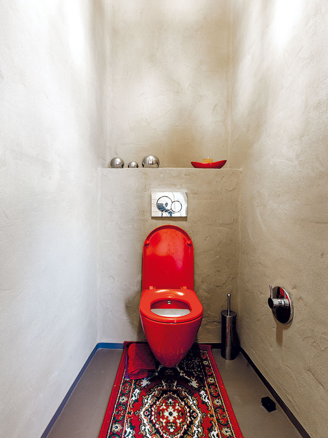 Kombinace hliněné omítky, červených a stříbrných doplňků dodává toaletě specifický, příjemně působící charakter. FOTO DANO VESELSKÝ