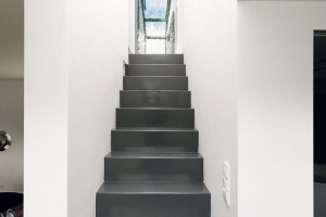 Úzké ocelové schodiště, které vede do druhého podlaží, vedle své praktické funkce plní i roli působivého estetického prvku v interiéru. FOTO Dano Veselský
