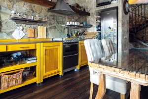 Přímá kuchyňská linka s vyzděným prostorem na chladničku, vyrobená ze světlého masivu se žlutým nádechem, kontrastuje s ostatním, převážně tmavým dřevem. Kuchyňskou zástěnu tvoří obklad z pískovce, který najdete i u schodiště nebo v koupelně. FOTO DANO VESELSKÝ