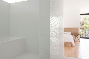 Přestože nemá dveře, postavení stěn zachovává koupelně soukromí. Ve snaze navodit maximální pocit čistoty, architekti ji zahalili do do mozaiky z bílého skla a vybavila jen bílým nábytkem a předměty. Foto: Maxime Brouillet