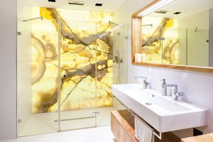 Dominantou koupelny je stěna z onyxu, která tvoří zadní stěnu sprchového koutu a celý prostor prosvětluje.
