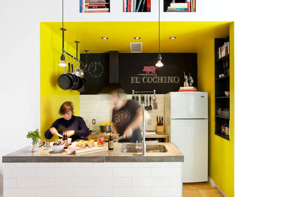 Miniaturní kuchyňská linka je zapuštěna v nice, kterou oživuje žlutý nátěr na stěnách. Malou pracovní plochu doplňuje vysunutý kuchyňský pult, který je středobodem celého prostoru. FOTO ADRIEN WILLIAMS