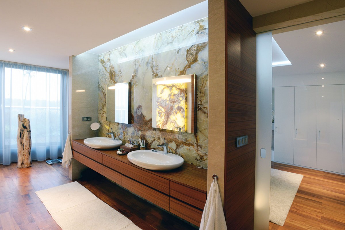 Koupelna „en suite“. Na ložnici majitelů přímo navazuje elegantní prostorná koupelna. Dominuje jí týkové dřevo, které dobře odolává vodě. FOTO KOSI ARCHITEKTI