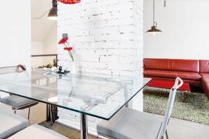 Vtipné designové svítidlo od Ingo Maurera je jedním z mála výrazných barevných akcentů v interiéru. Skleněný jídelní stůl se židlemi – stejně jako koženou sedačku – si Radek přinesl z předchozího bydlení. FOTO DANO VESELSKÝ