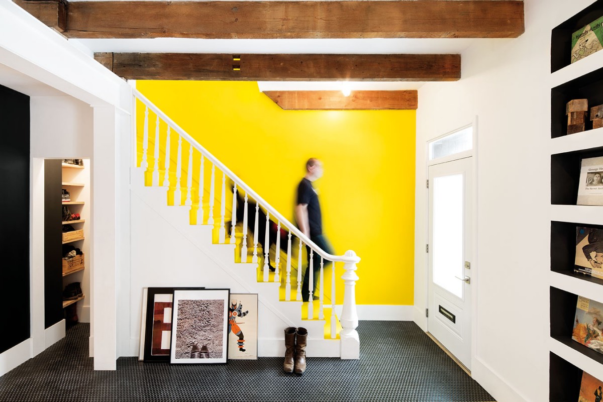 Žlutá je oblíbenou barvou mladého páru. Často je k vidění i u jejich předchozích projektů. Ve vstupní hale se za schodištěm do prvního patra důmyslně skrývá botník a prostor pro odkládání věcí. FOTO ADRIEN WILLIAMS