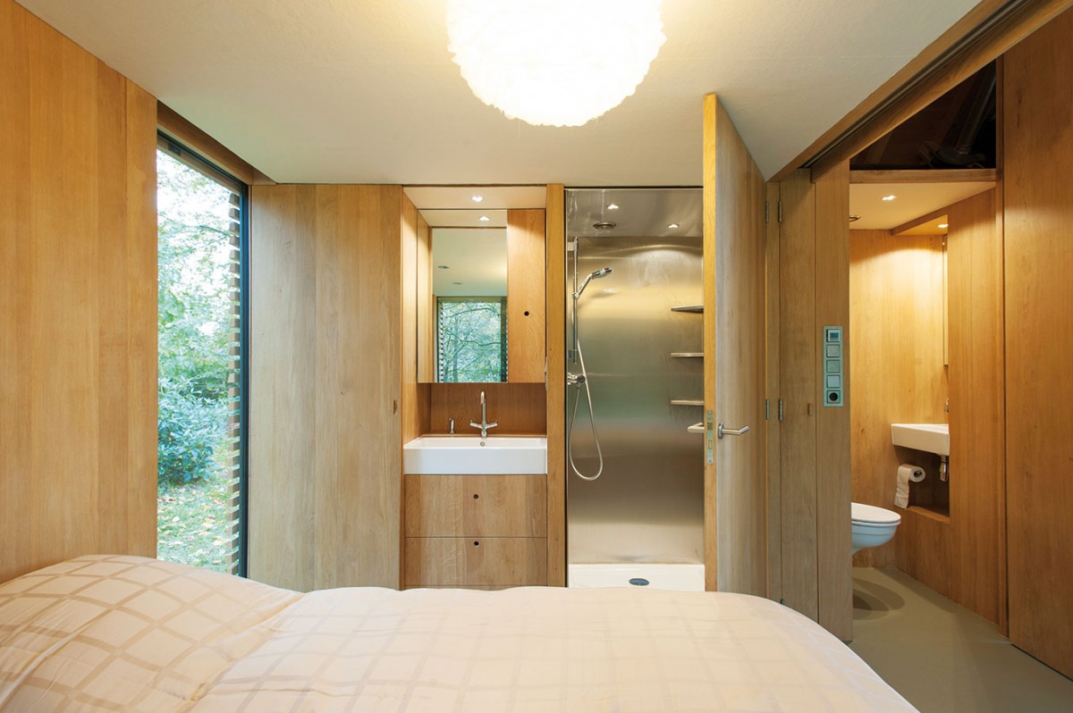 Stěna z dubového dřeva, kterou z druhé stěny kryje plná břidlicová fasáda, v sobě kromě běžných úložných prostor skrývá také kuchyňskou linku a toaletu, ve spací části pak také jednoduchou koupelnu (umyvadlo a sprchový kout). FOTO ROEL VAN NOREL