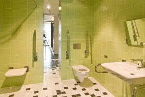 Bez bariér ve využití, i v designu, taková je komfortní koupelna pro handicapované se sérií KOLO Nova Pro Bez Bariér a s oddáleným ovládáním splachování Geberit Sigma70 v nerezu.
