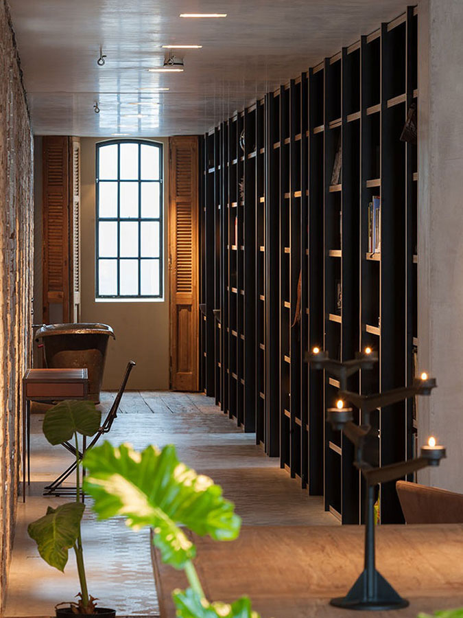 Skutečně netradičně – přímo na chodbě – se nachází minimalistická koupelna, která je prostřednictvím knihovních polic propojená s ložnicí. Foto: Teo Krijgsman