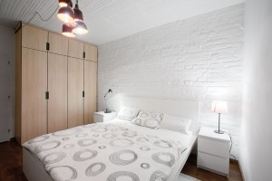 Nábytek na míru v dřevěném dekoru je odlišený od typového. Ten je v případě ložnice jednoduchý bílý, vystihující pánskou ležérní eleganci. FOTO TOMÁŠ MANINA