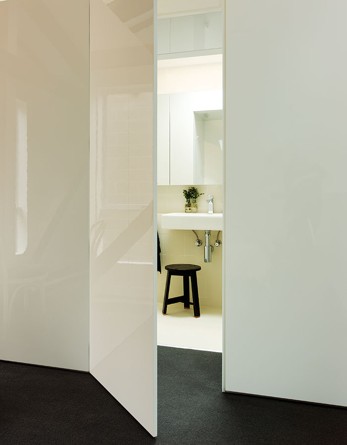 Koupelna se skrývá za sestavou několika bílých dveří a je zařízená ve stejně minimalistickém duchu jako ostatní prostory. FOTO Ben Hosking (techne.com.au)