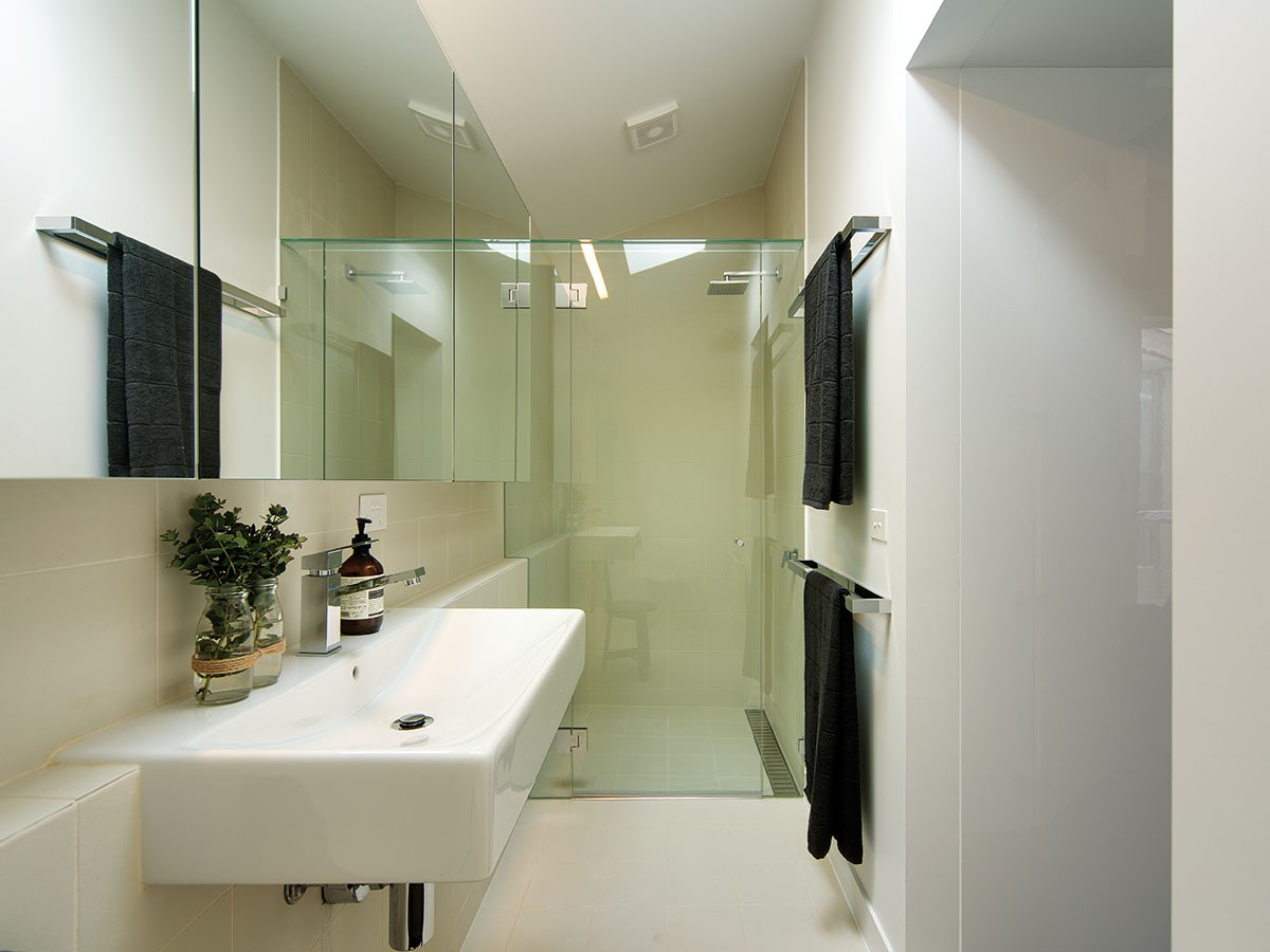 Jednoduchou bílou barevnost v koupelně doplňují zrcadlové a skleněné plochy. Prostor opticky zvětšují a dodávají mu lesk. FOTO Ben Hosking (techne.com.au)