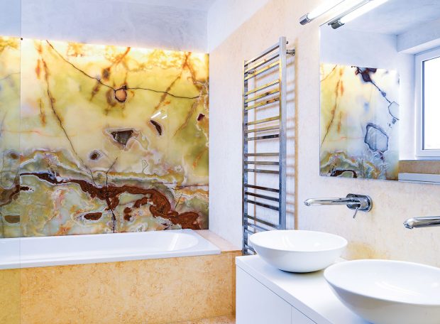 Kombinace podsvícené onyxové desky v koupelně a mramoru na podlaze a dalších částech obložení připomíná antické lázně. Kombinace s bílými zařizovacími předměty celý efekt zjemňuje. FOTO ATELIÉR SENAA