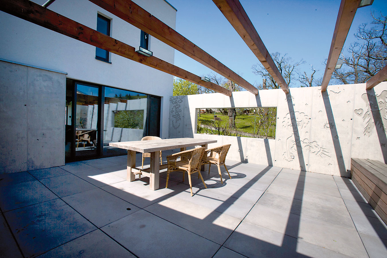 Severní terasa či spíše patio chráněné stěnami z grafického betonu poskytuje v létě příjemný stín. Dřevěná konstrukce nad terasou je naplánována jako opora pro vistárii, která tu časem vytvoří ještě příjemnější mikroklima. Foto ITB Development