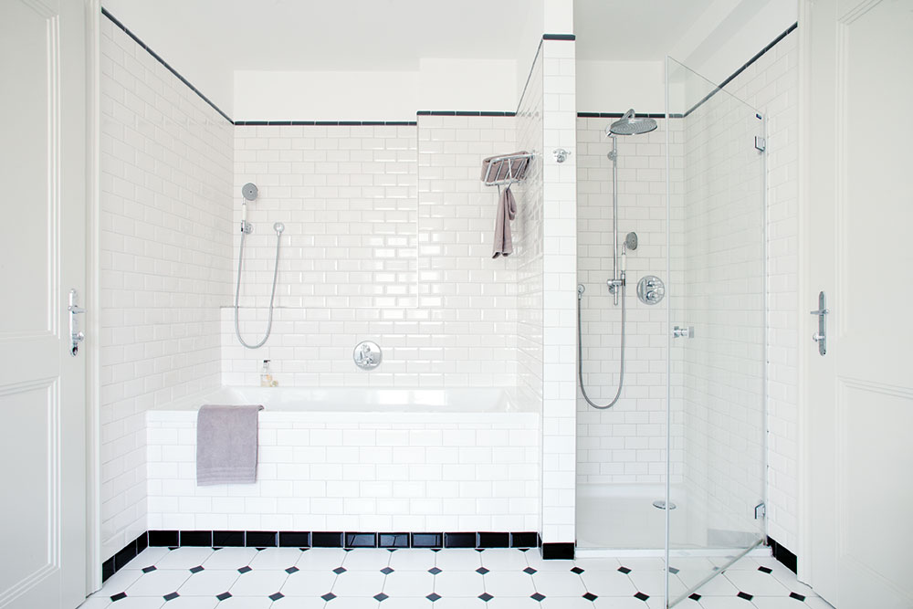 V prostorné koupelně v horním patře je k dispozici jak vana, tak sprchový kout s věrnými replikami dobových sprchových hlavic. Jednoduchý obklad a bílo-černá podlaha dotvářejí elegantní a čistý vzhled místnosti. FOTO ROBERT ŽAKOVIČ