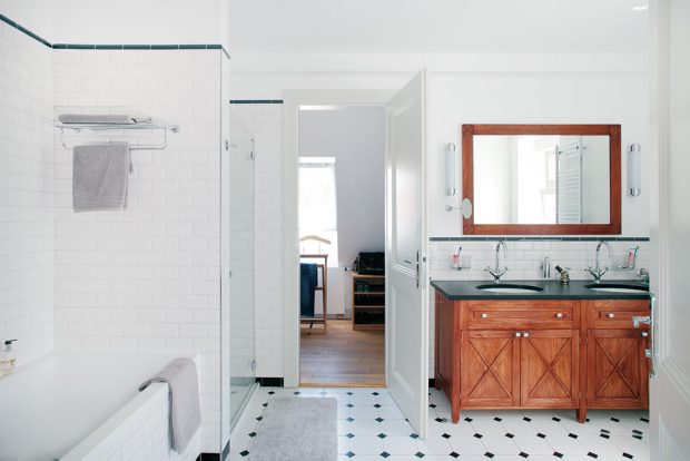Koupelna je průchozí ze dvou stran. Z ložnice majitelů je praktický přístup přes šatnu. V jednoduché místnosti se krásně vyjímají i dřevěné umyvadlové skříňky a zrcadlo s dřevěným rámem. FOTO ROBERT ŽAKOVIČ