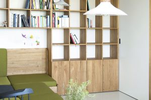 Oživujícím prvkem denní části je zelené čalounění sedačky. Její korpus je vyroben z téhož dubového dřeva jako knihovna i část kuchyňské linky, což prostor sjednocuje. FOTO SCHWESTERN