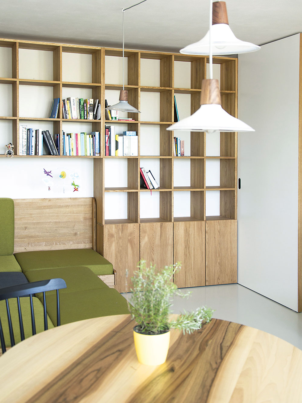 Oživujícím prvkem denní části je zelené čalounění sedačky. Její korpus je vyroben z téhož dubového dřeva jako knihovna i část kuchyňské linky, což prostor sjednocuje. FOTO SCHWESTERN
