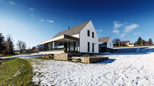 Celý dům je navržen v kombinaci bílé a šedé barvy v několika sytostech. Neutrální světlá barva omítky doplňuje lomový kámen použitý na obložení soklu a dřevěný obklad terasy. FOTO Kamil Saliba