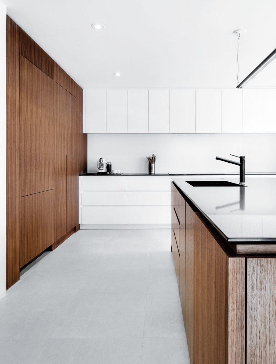 Kombinace bílých skříněk s tmavým dřevem nechává vyniknout minimalismus kuchyně. Dalšími barvami by se tato jednoduchost vytratila. Foto v2com