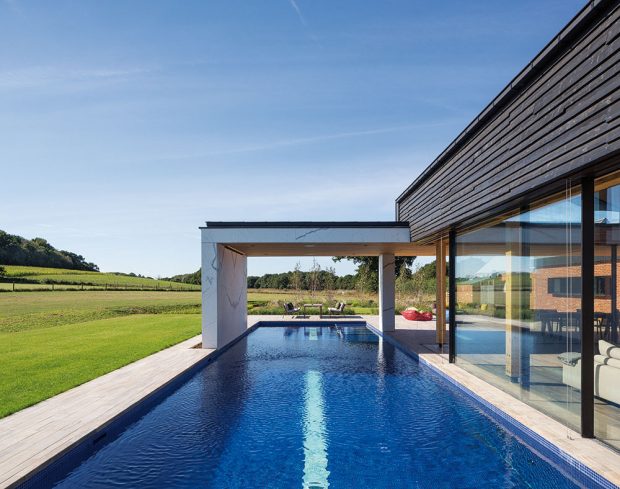 Dlouhý bazén kopíruje jednu stěnu domu. Prosklené okenní tabule se dají posouvat a voda tak téměř prostupuje interiér. FOTO DIRK LINDNER PRO KETTAL