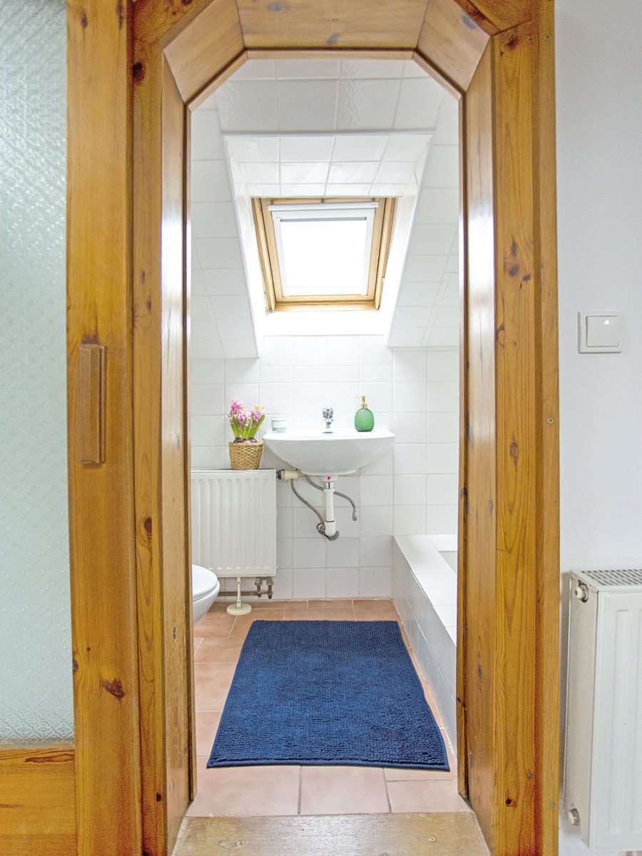 Za dřevěným portálem se ukrývá malá koupelna se sprchovým koutem. foto www.browneyedcouple.com
