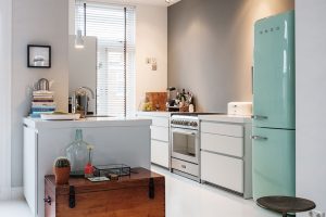 Kombinace světle modré retro lednice Smeg a dřevěné truhly přesně vystihuje Odettinu zálibu v různých stylech. Foto Femque Schook pro Westwing Home and Living