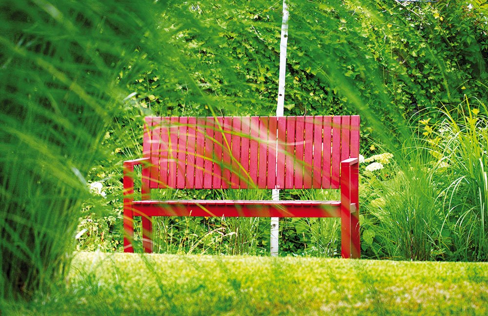 Barevný akcent můžete do zahrady poměrně snadno vnést výběrem zahradního nábytku. Do této minimalistické architekti navrhli červené lavičky, které ji vkusně dotvářejí. FOTO ATELIER FLERA