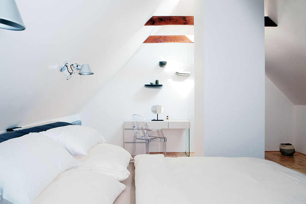 Světlou, bílou ložnici pro hosty, která se nachází v prvním patře, zdobí mimo jiné elegantní průhledná židle. foto Robert Žákovič