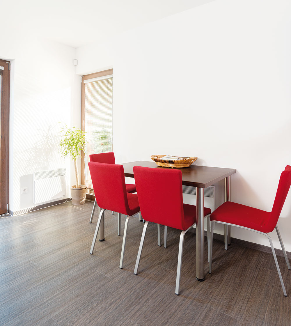 Červené kuchyňské židle oživují střídmý interiér. Foto RD Rýmařov